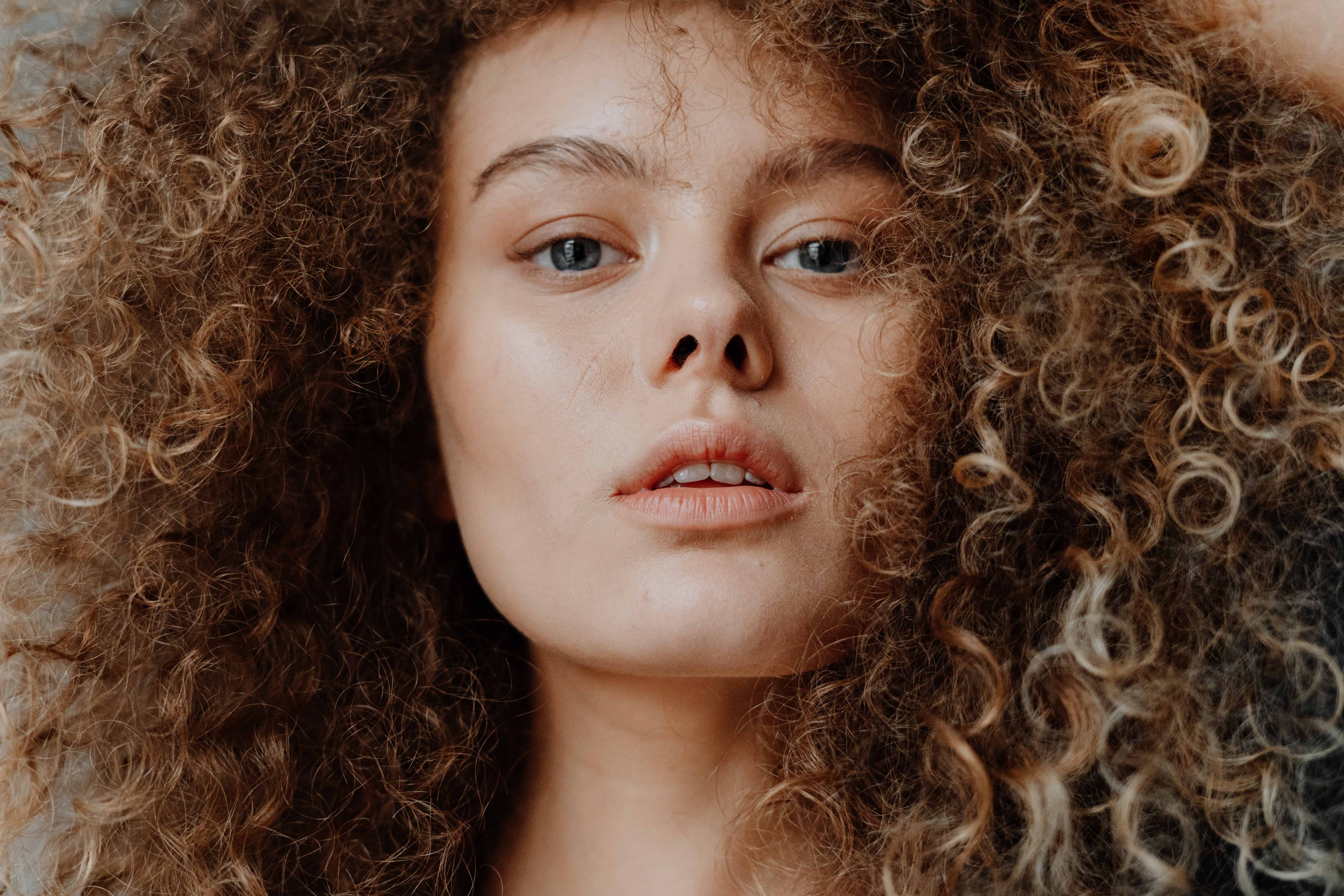Close-up van een vrouw met volle blonde krullen
