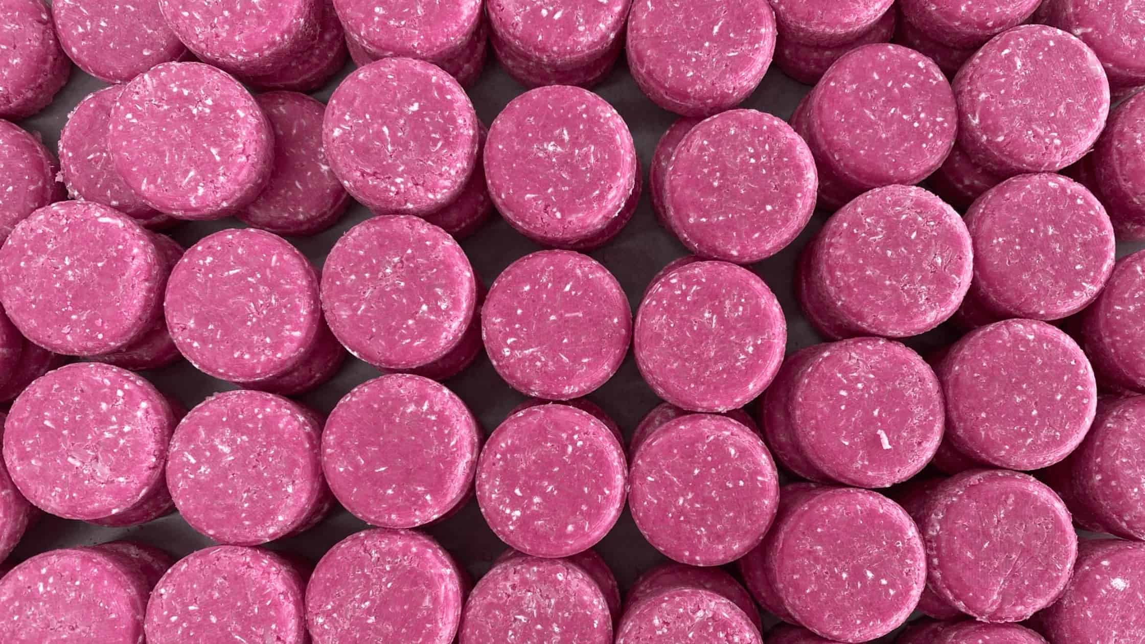 Groot aantal roze shampoo bars naast elkaar, van bovenaf gezien